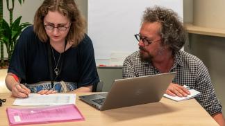 Steven Claeyssens kneeling next to Iris Geldermans working behind a laptop