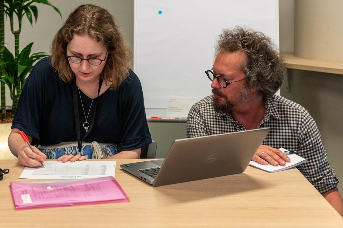 Steven Claeyssens kneeling next to Iris Geldermans working behind a laptop