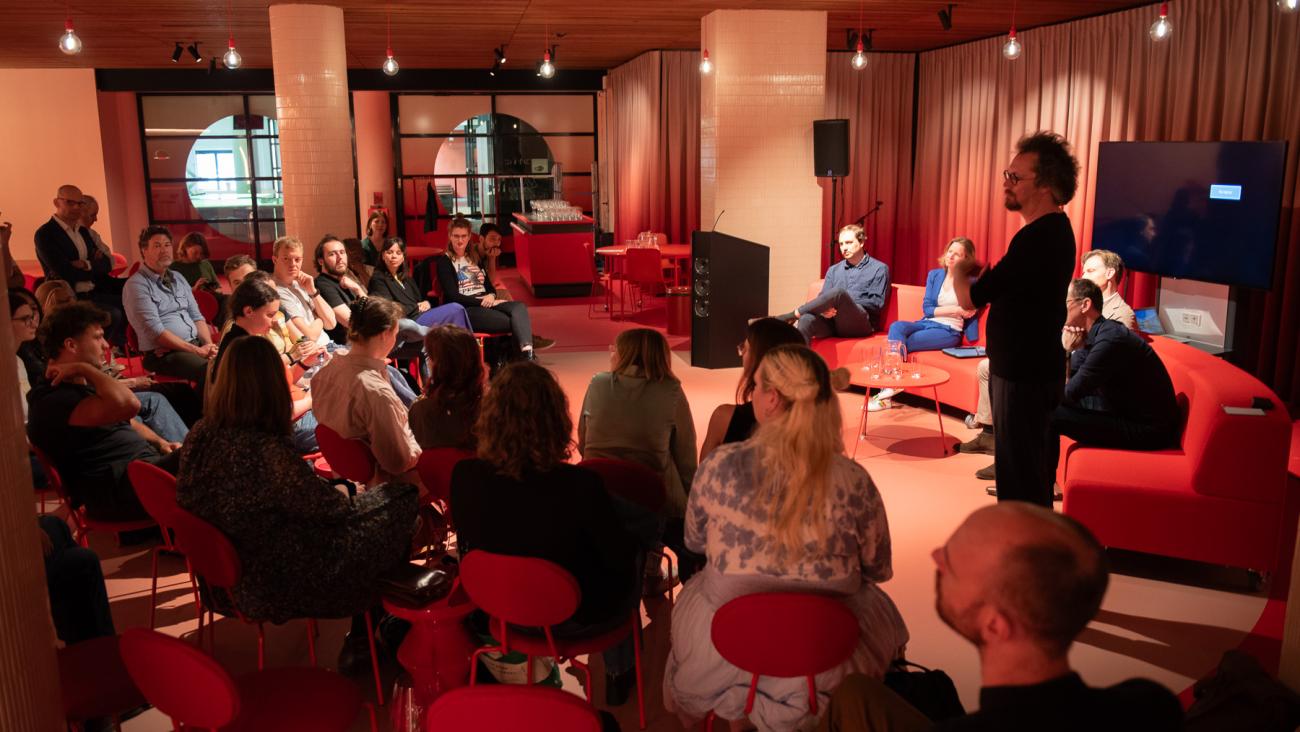 Panel of four people sitting on the sofa. The presenter standing before, all looking at the audience