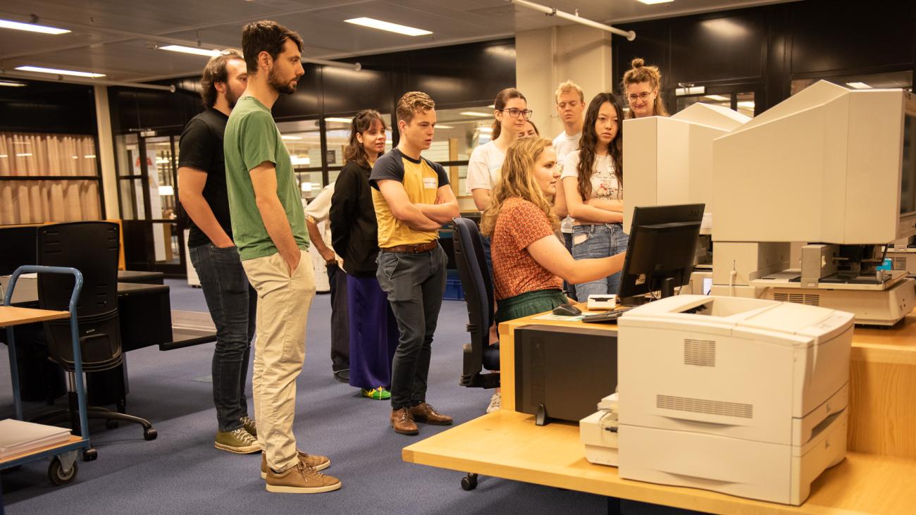 A woman behind a computer showing the group standing behind her something